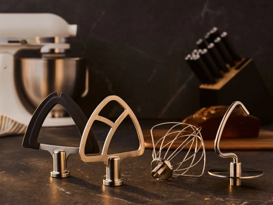 KitchenAid Artisan Plus mixer with its included beaters, dough hook and whisk on a countertop